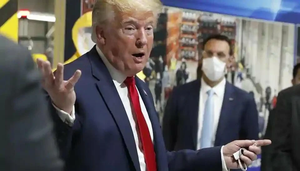 In this May 21, 2020 file photo, President Donald Trump holds a face mask in his left hand as he speaks during a tour of an automobile plant that has been converted to making personal protection and medical equipment, in Ypsilanti, Michigan.