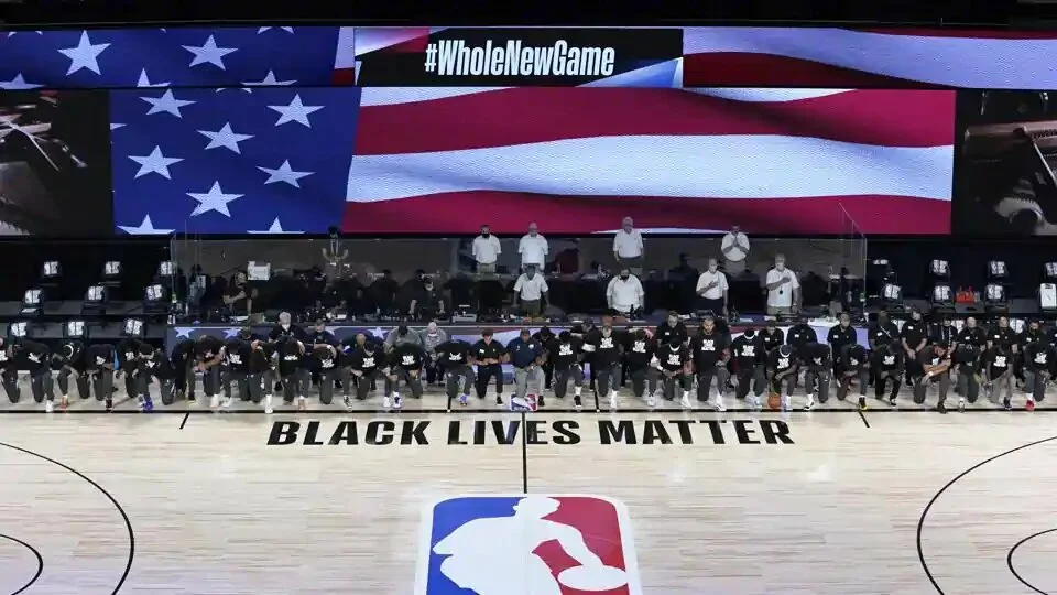Members of the New Orleans Pelicans and Utah Jazz kneel together around the Black Lives Matter logo on the court during the national anthem before the start of an NBA basketball game.